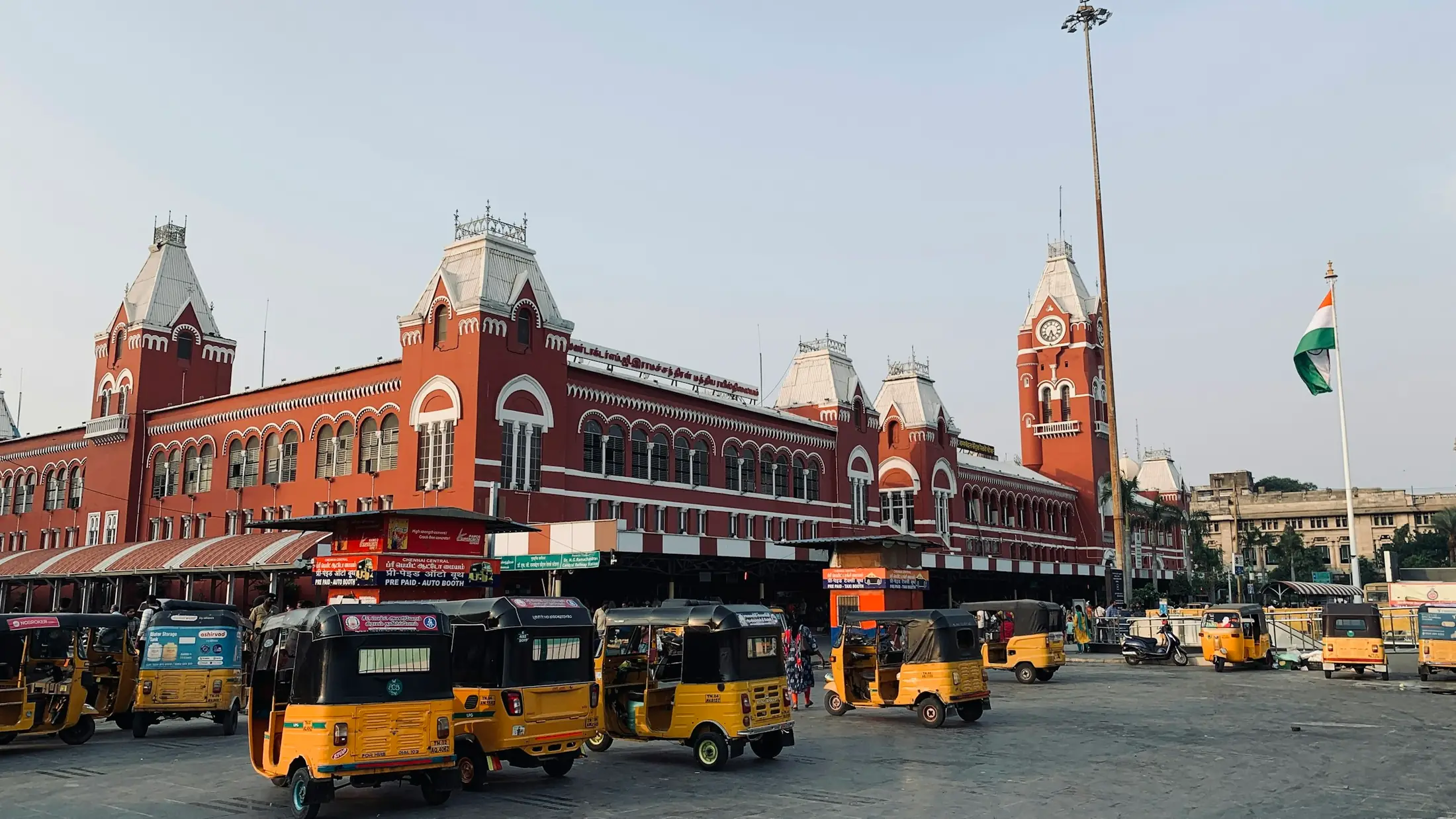 Chennai Central railway station's red heritage facade with yellow auto-rickshaws in front