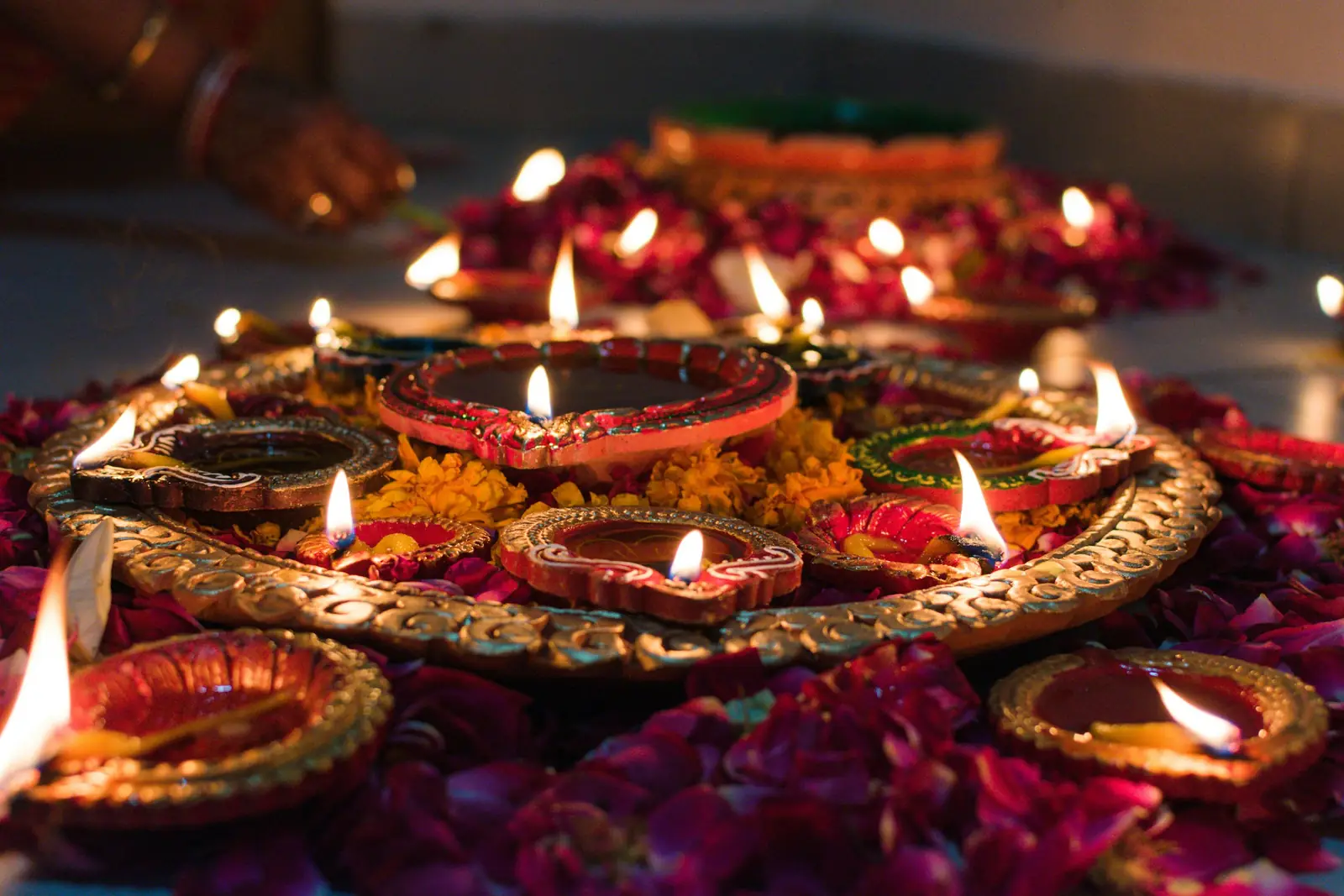 Lit clay diyas on a decorative tray surrounded by flower petals