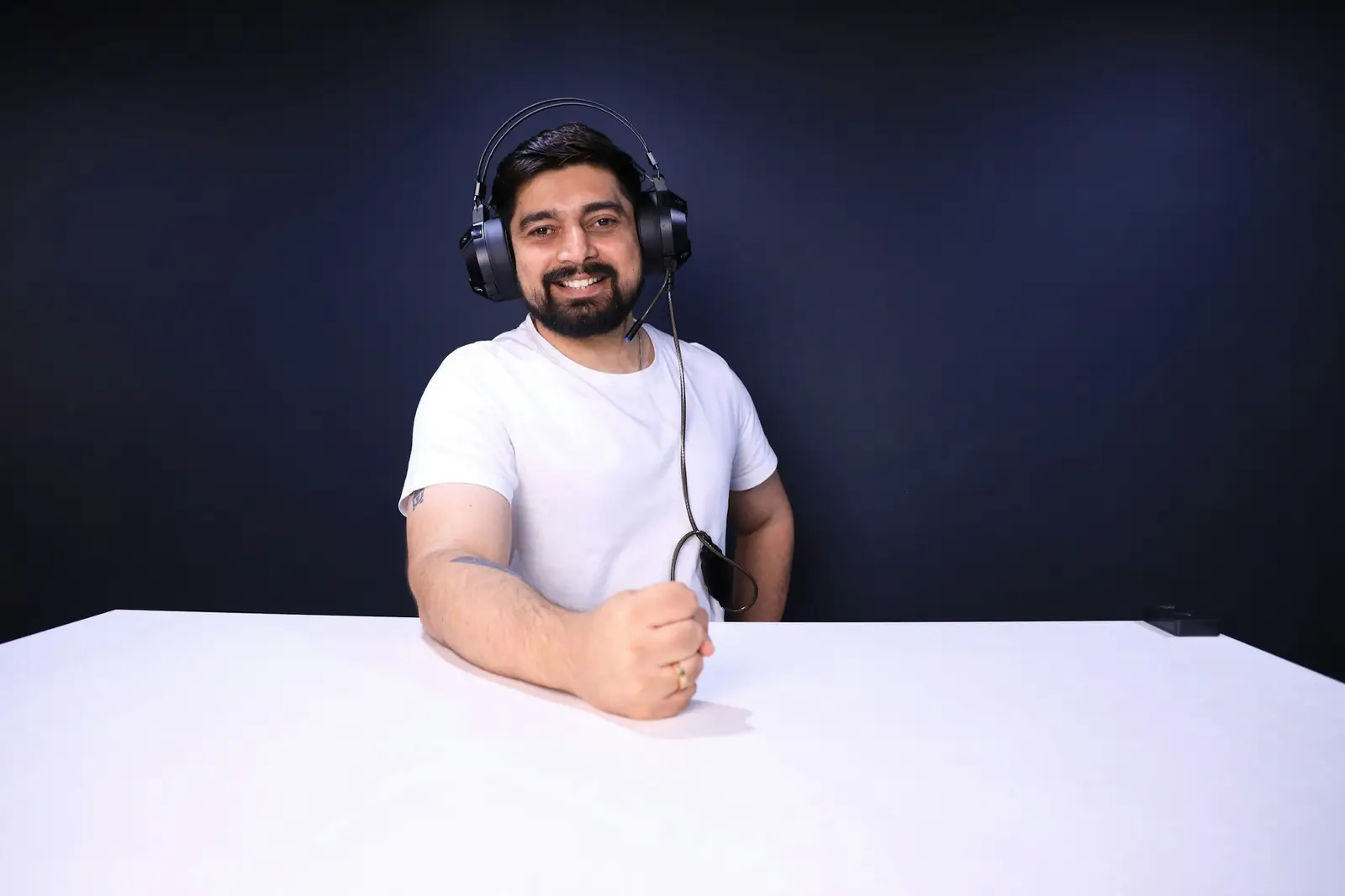 A man wearing headphones seated at a table, recording